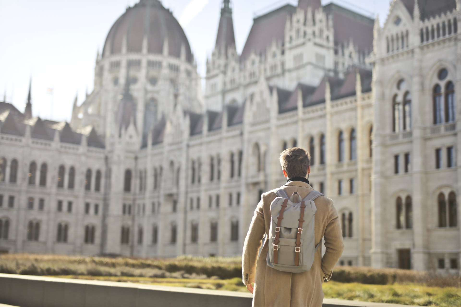 Young man with a backpack in front of the Hungarian Parliament Building in Budapest